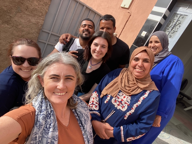       Group of people taking a smiling selfie outside.
  