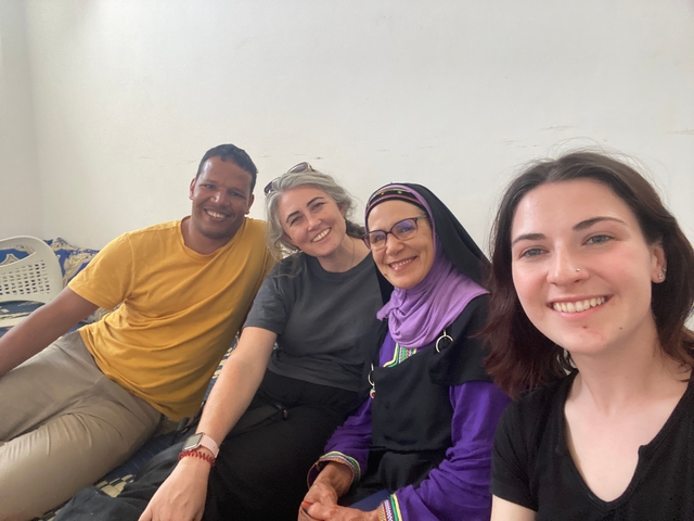 A group of four people sitting and smiling indoors.