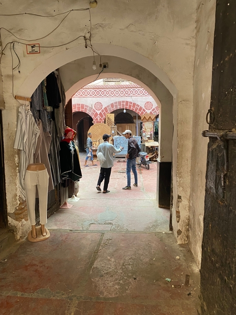       Two people standing in a narrow alleyway lined with merchandise.
  