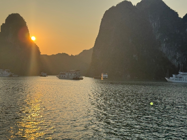       Boats on water with steep cliffs at sunset.
  