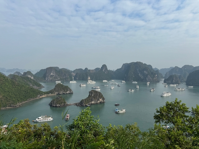Many boats sailing past islands in bay.