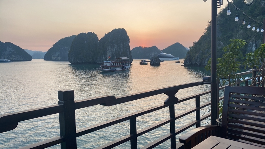       Sunset view of Halong Bay with boats on the water.
  