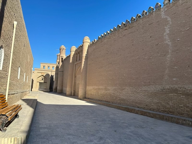       Scenic alley between ancient city walls under a bright blue sky.
  