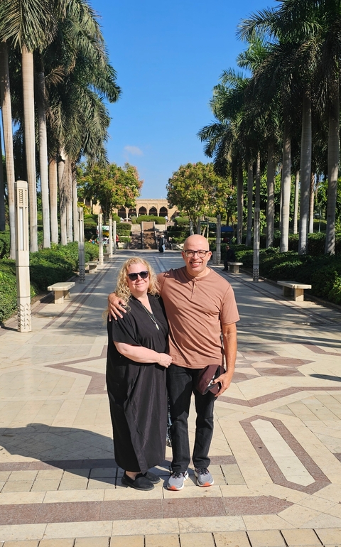 A couple posing in a beautifully landscaped garden with palm trees.