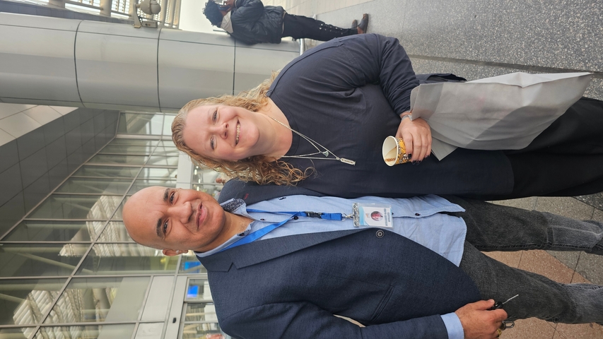 A couple posing in front of an airport or transport building.
