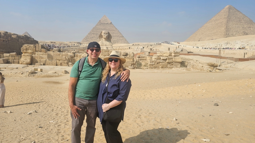       Two people posing with the Great Sphinx and a pyramid in the background.
  