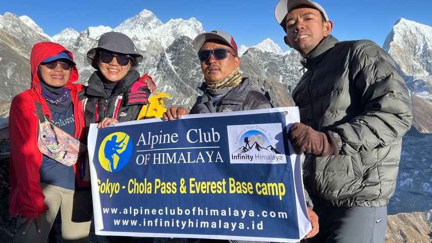       People holding a sign with snow-covered mountains.
  