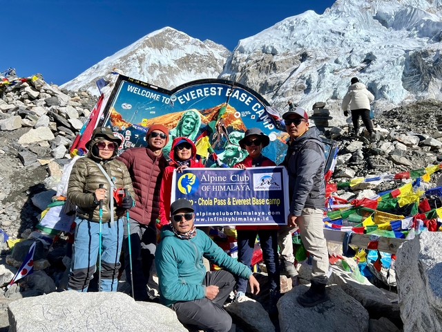       Group at Everest Base Camp with colorful flags.
  