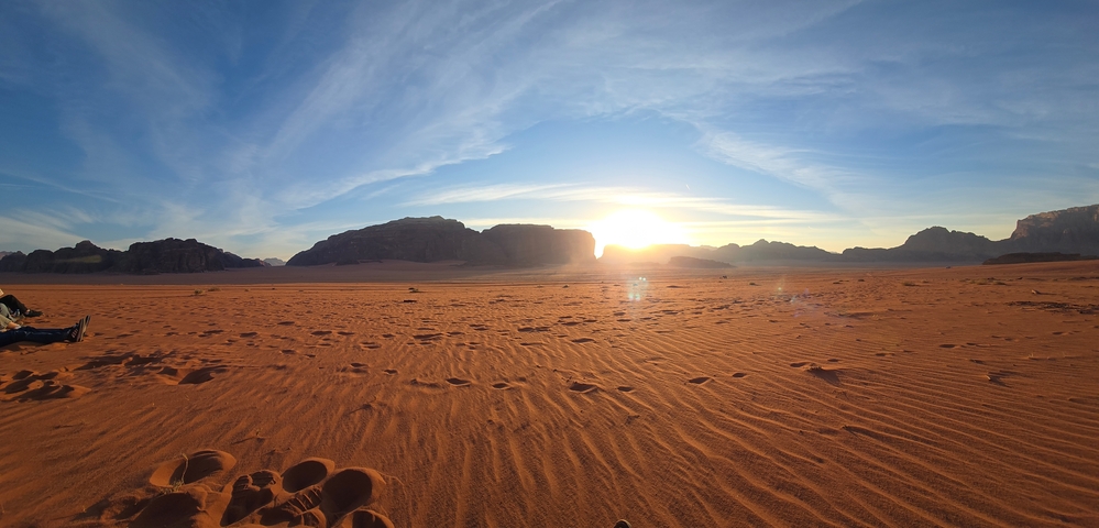 Desert landscape with sun setting over distant mountains