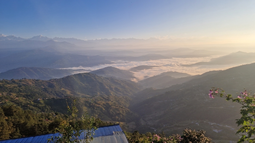       A misty view of mountains with a valley covered in clouds during sunrise.
  
