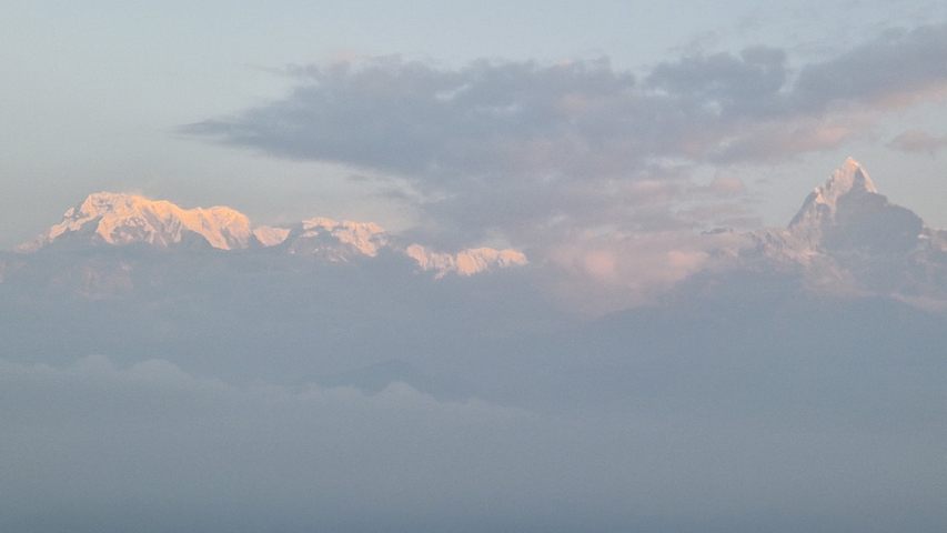       Snow-capped mountains under a cloudy sky, with soft lighting.
  