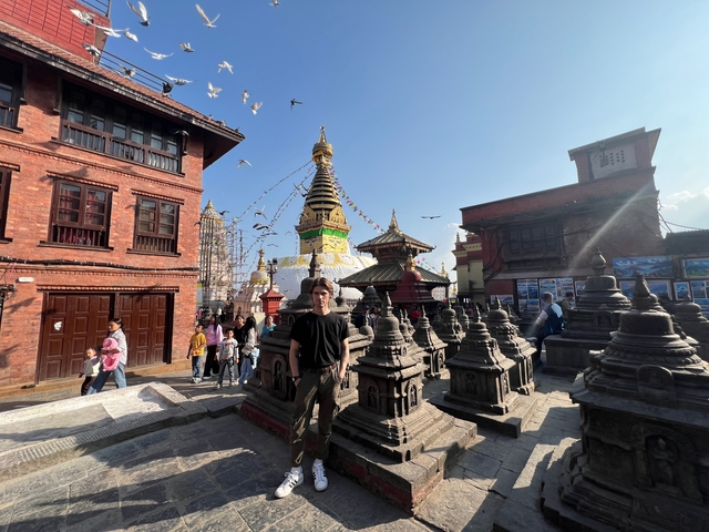 A bustling square with a golden stupa and traditional architecture.