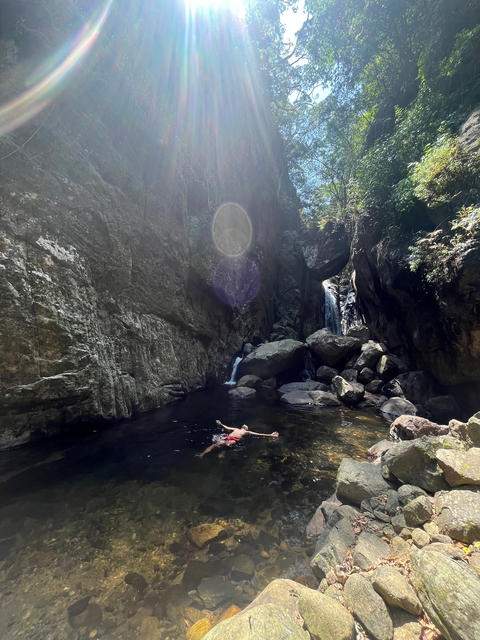 Person swimming in a water pool within rock formations.