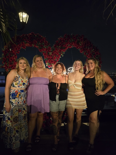 Group of women posing in front of a floral display at night