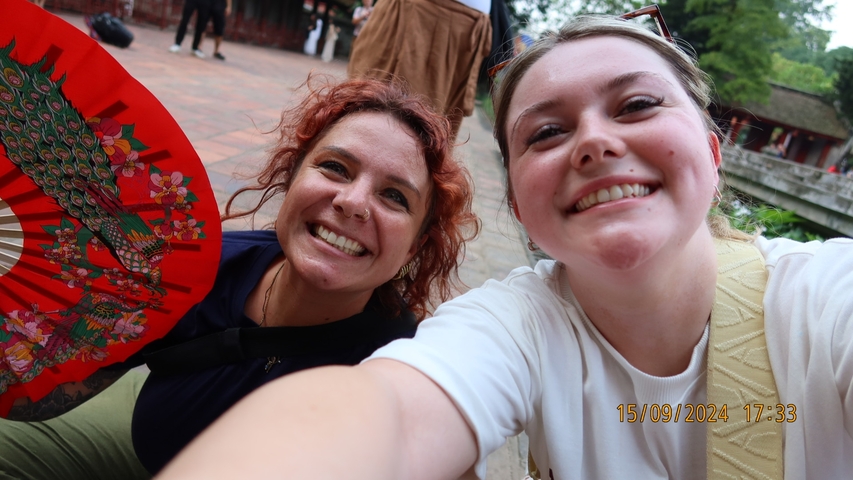 Two women smiling with a decorative fan