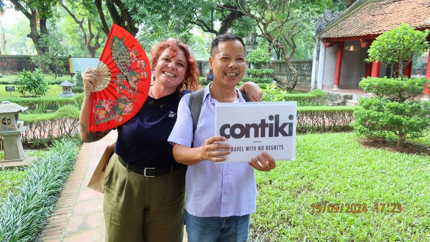 Woman with a decorative fan posing with another person holding a sign
