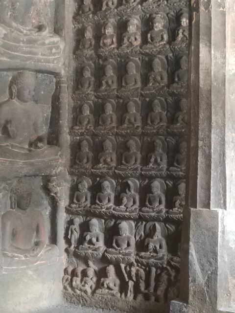 Wall with multiple small Buddha statues carved into it.