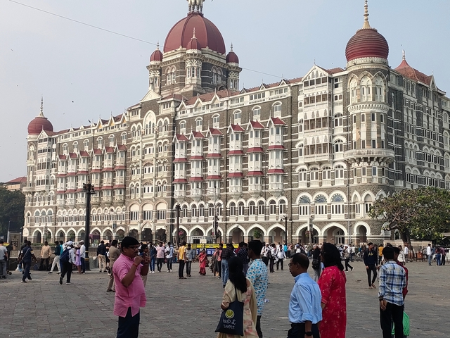 Large historic hotel with people walking in front of it.