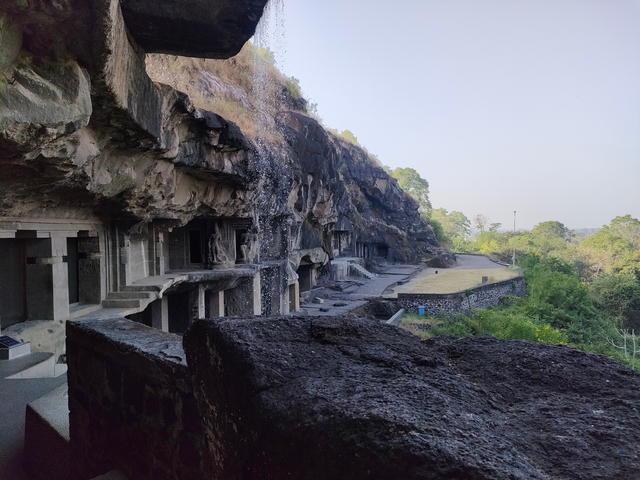 Series of ancient caves carved into a cliff under a clear sky.