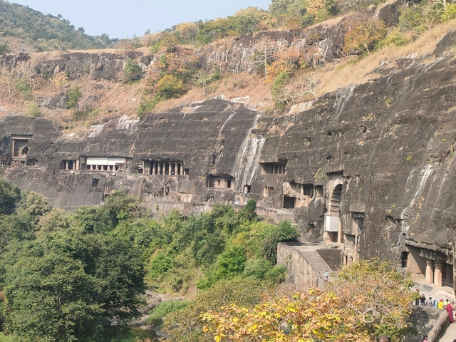 View of a series of caves in a lush, green landscape.