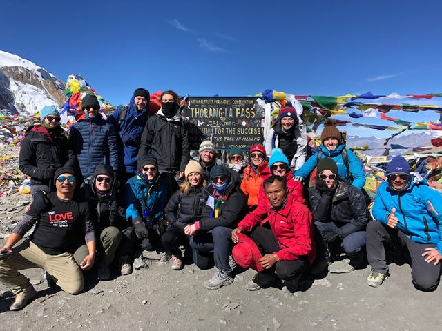 Group of people at Thorong La Pass with prayer flags.