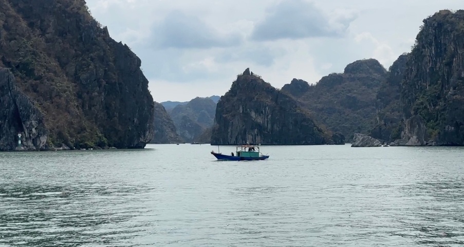 A scenic view of limestone karsts and a boat on calm waters.