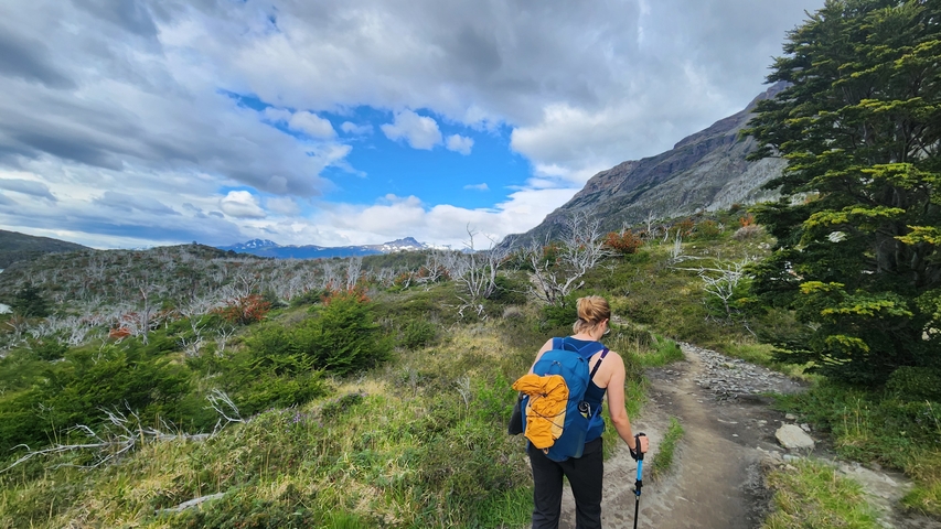       Hiker walking along a scenic trail surrounded by mountains.
  