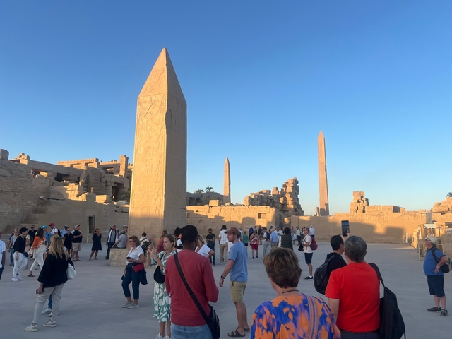Tourists visiting a temple complex with obelisks.