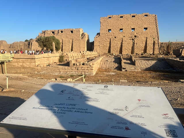 Tourist site with ruins and informational sign in Luxor.