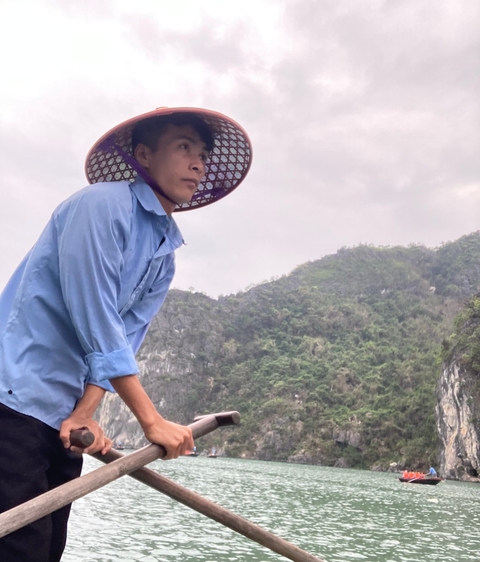       Man rowing a boat in a scenic landscape.
  