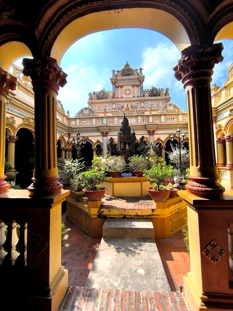       Ornate temple courtyard with plants and sculptures.
  