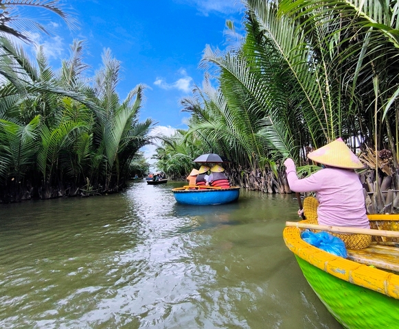       People in round boats rowing through palms on a river.
  