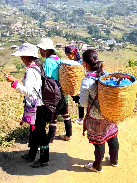       Women carrying baskets walking through fields.
  