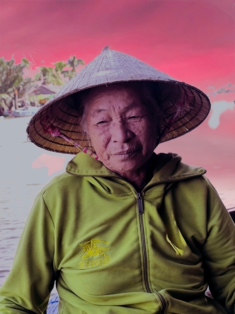 Portrait of an elderly woman wearing a traditional conical hat.