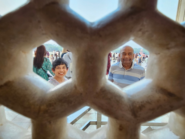 Two people looking through a decorative stone frame.