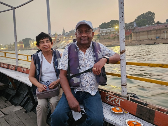Two people on a boat with riverside buildings in the background.