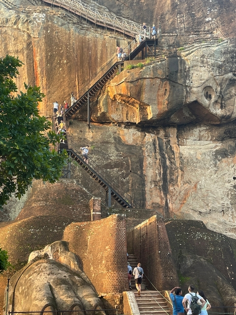 People climbing steps on a large rock structure.