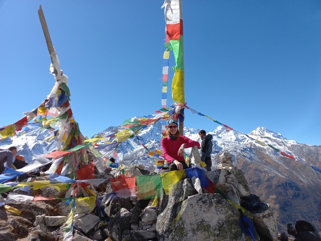 Person with prayer flags in a mountainous landscape.