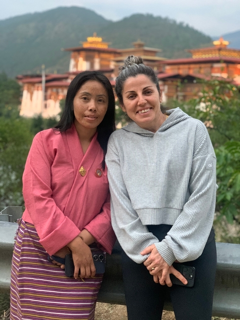 Two women posing together in traditional Bhutanese outfits.