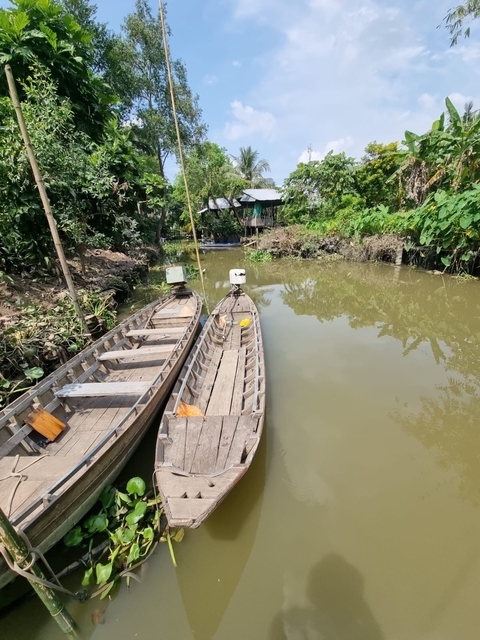 Two wooden boats on a narrow water canal surrounded by greenery.