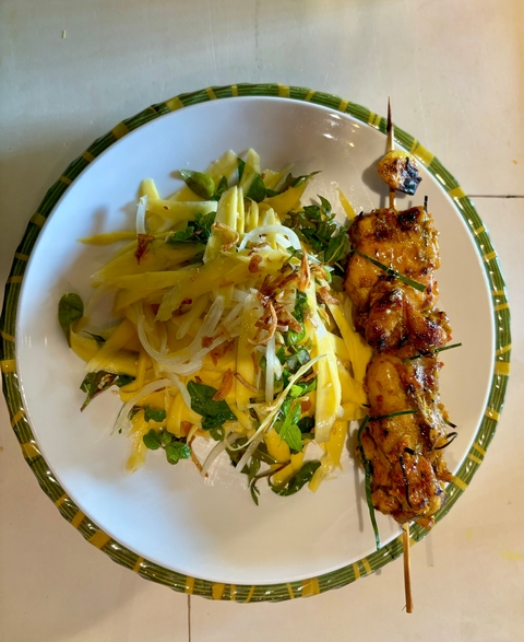       Plate with a dish of skewered meat and pickled vegetables.
  