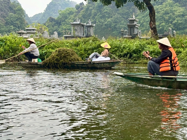 Three people rowing in traditional boats on a river.