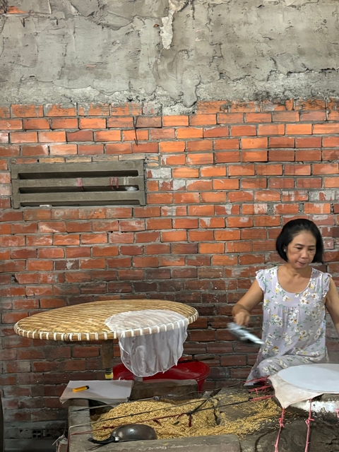       Woman in a brick-walled room engaged in crafting.
  