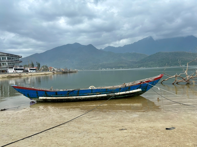       Traditional boat on a calm river with a mountainous backdrop.
  