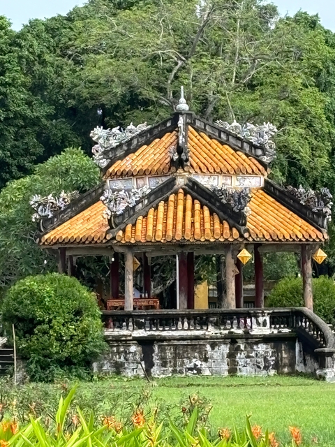       Traditional temple with ornate roof tiles and decorations surrounded by trees.
  