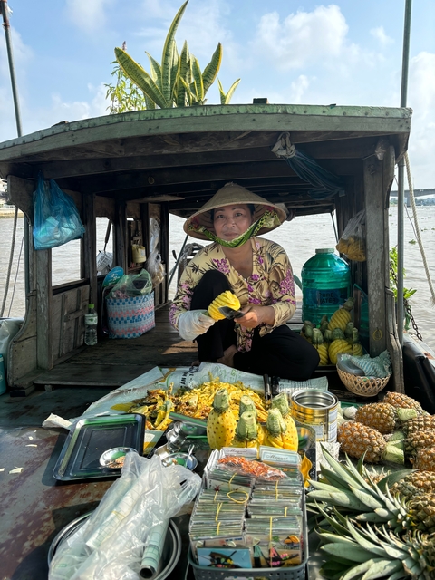       Woman preparing fruit on a boat with a makeshift kitchen.
  