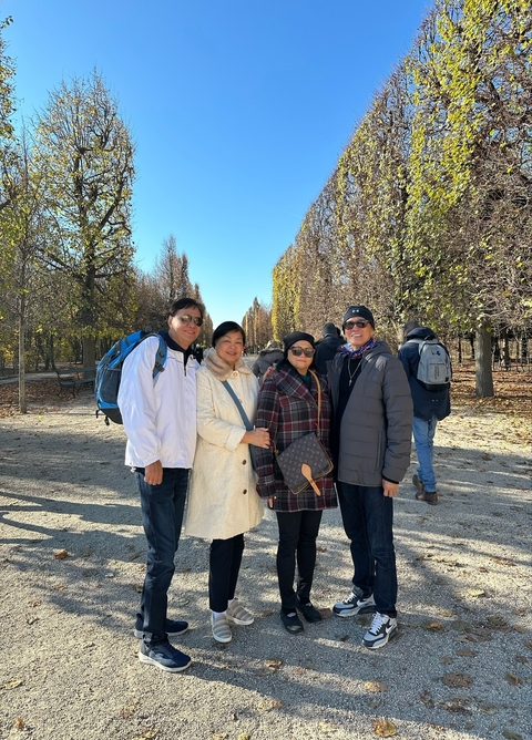 Four people standing in a tree-lined avenue on an autumn day.