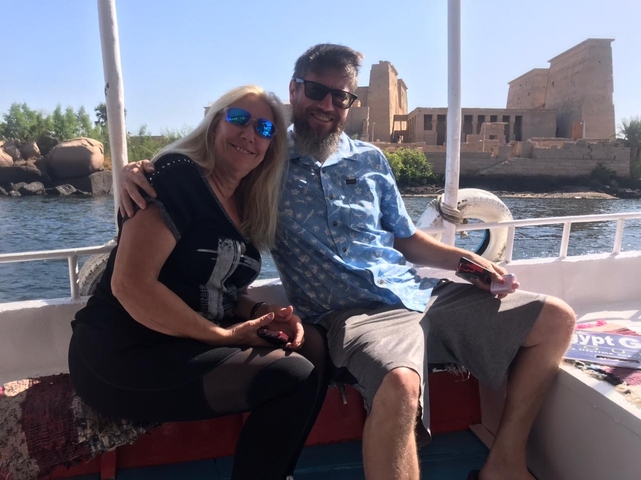Couple enjoying a boat ride with a historical site in the background.