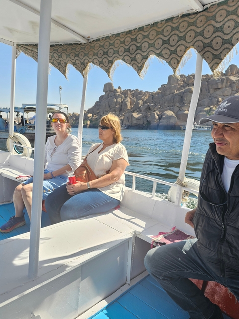       Tourists sitting in a motorboat on a river with rocky background.
  