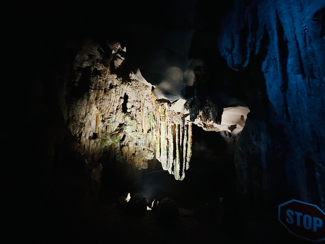 Cave interior with stalactites, partially illuminated.